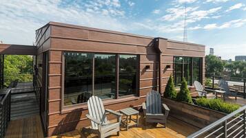 Un edificio moderno con ventanas amplias y una terraza de madera con sillas Adirondack.