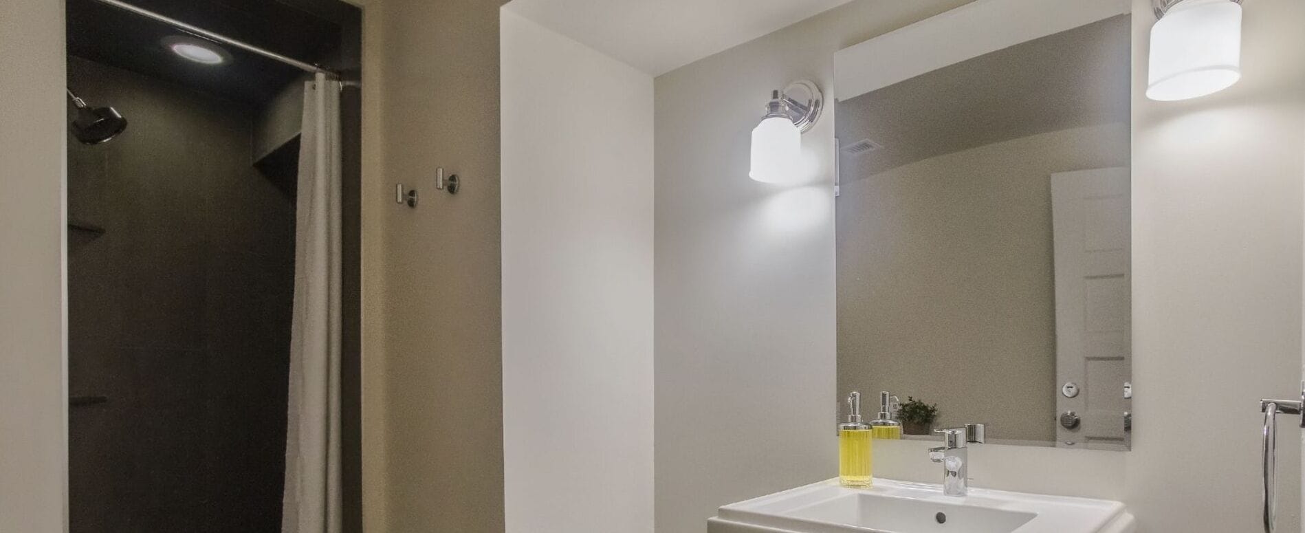 Een moderne badkamer met een witte wastafel, spiegel en douche.