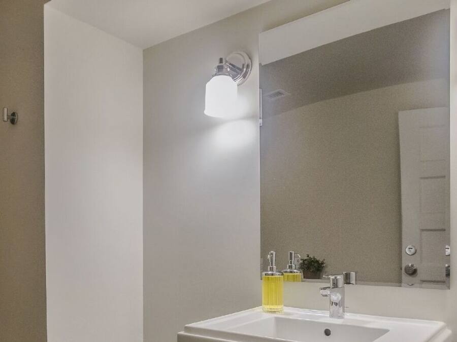 A modern bathroom with a white sink, mirror, and shower.
