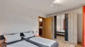 A modern bedroom with two beds, a wardrobe, and a small table. - Apartment in Kleines Wiesental (Kleines Wiesental - Raich)