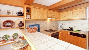 Une cuisine avec des meubles de rangement en bois, une cuisinière, un évier et divers ustensiles de cuisine rangés sur des étagères.