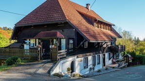 Een klassiek chalet met een steil dak, een houten veranda en een klein balkon.