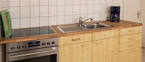 A kitchen with wooden cabinets, a stainless steel sink, a coffee maker, and a built-in oven.