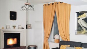 Un salón con chimenea, un sofá, una mesa de centro y un cuadro de un pájaro.