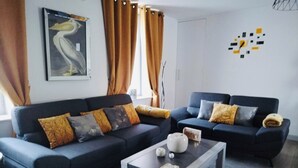 Una sala de estar moderna con dos sofás oscuros, una mesita de centro y un cuadro de un pájaro en la pared.