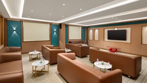 Un espace de détente moderne avec des canapés, des tables et un grand téléviseur à écran plat.