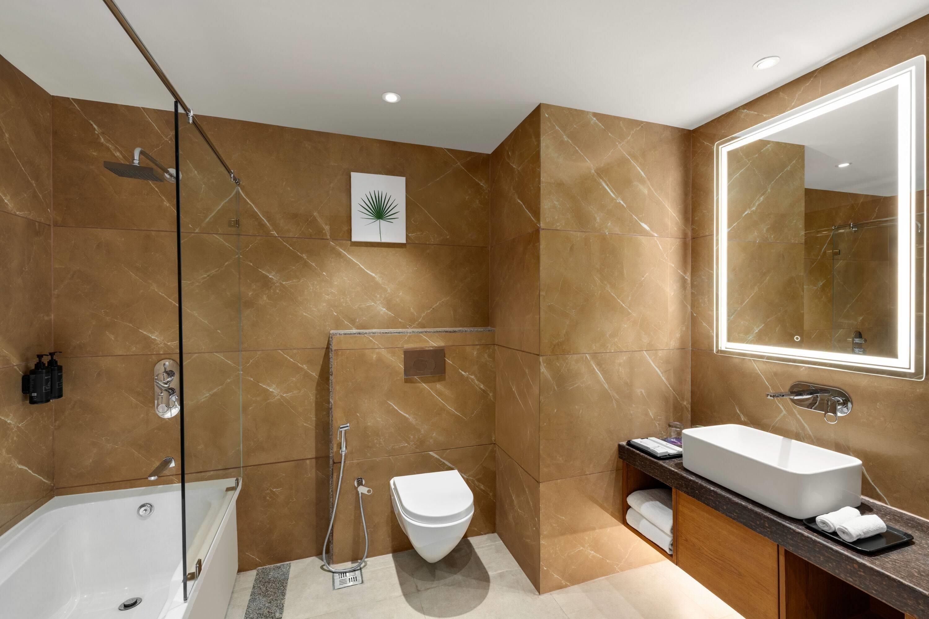 A modern bathroom with a bathtub, a toilet, and a large mirror.