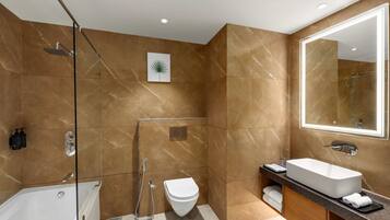 A modern bathroom with a bathtub, a toilet, and a large mirror.
