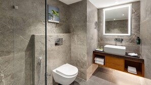 Une salle de bain moderne avec une douche à parois de verre, des toilettes blanches, un meuble-lavabo et un miroir.