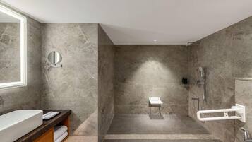 A modern bathroom with a large mirror, a built-in sink, a shower area, and a towel rack.