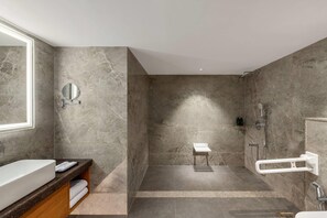 Ein modernes Badezimmer mit großem Spiegel, integriertem Waschbecken, Duschbereich und Handtuchhalter.