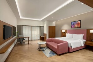 A modern hotel room with a large bed, a desk, a chair, and a TV. - Ramada Encore By Wyndham Viramgam (Viramgam)
