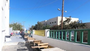 Un espace extérieur aménagé avec des tables et des chaises, un chemin pavé de pierres et un bâtiment blanc avec une clôture verte.