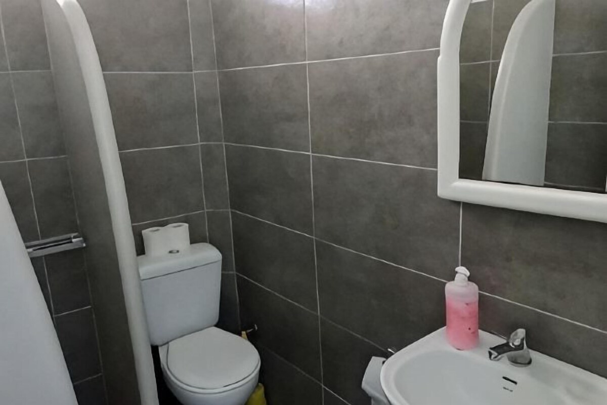 A bathroom with a toilet, sink, and mirror.
