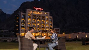 A couple dining outdoors at a hotel with a mountain backdrop.