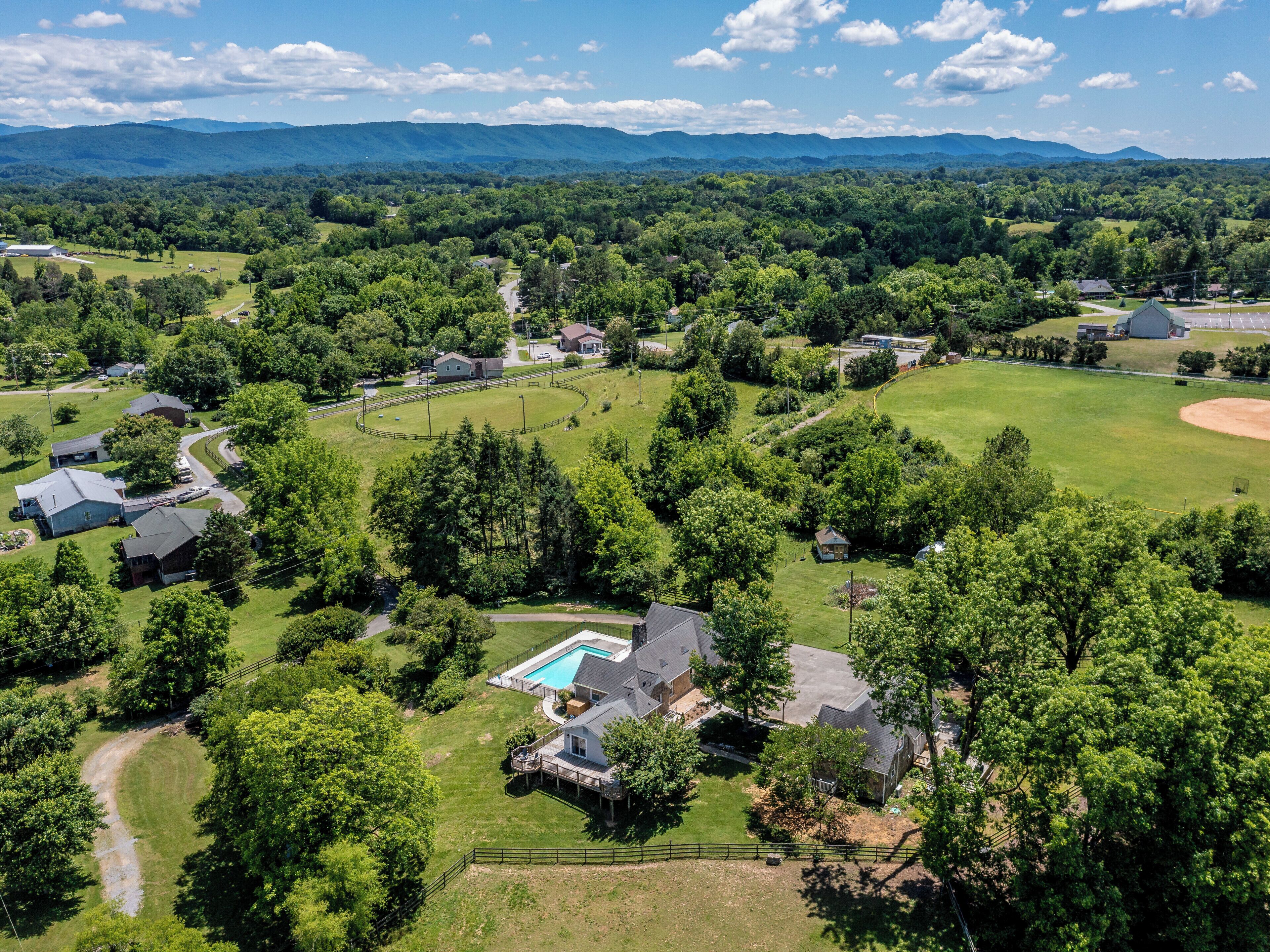 An aerial view of a residential area with houses, a swimming pool, and a baseball field.