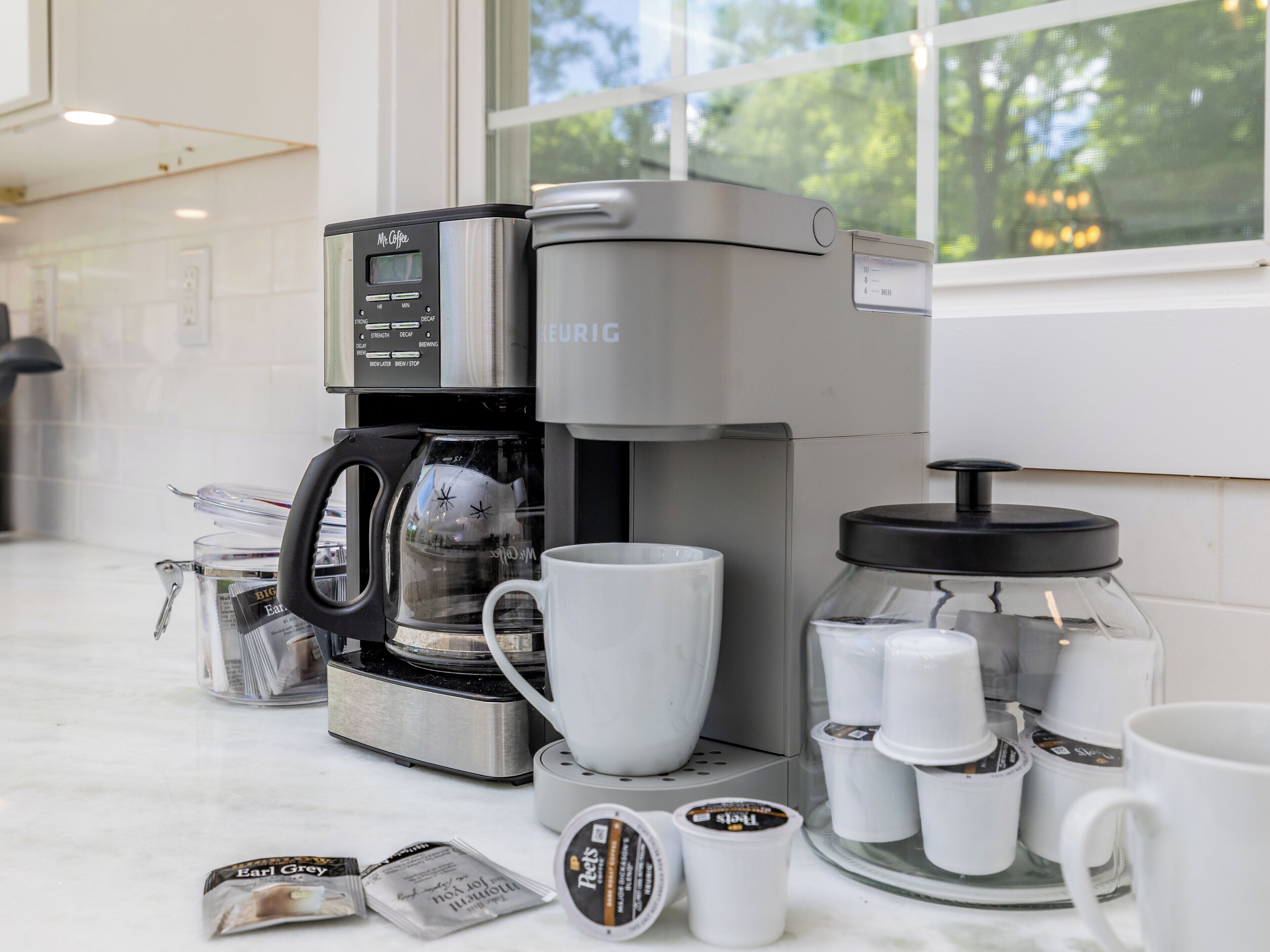 A modern kitchen with a coffee maker, coffee cups, and a glass carafe.