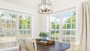 Ein Essbereich mit Holztisch, weißen Stühlen und einem Blumentopf.