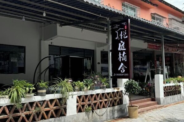 A building with a signboard and potted plants in front. - Yueting Nanshe Homestay (Renhua)