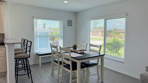 A dining area with a table and chairs, large windows with blinds, and a view of the outdoors. - Waterfront Retreat 4 BR, 3 BA screened & heated pool, gorgeous canal views (Rotonda West)