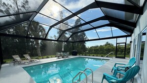 A covered swimming pool with lounge chairs and a patio area. - Waterfront Retreat 4 BR, 3 BA screened & heated pool, gorgeous canal views (Rotonda West)