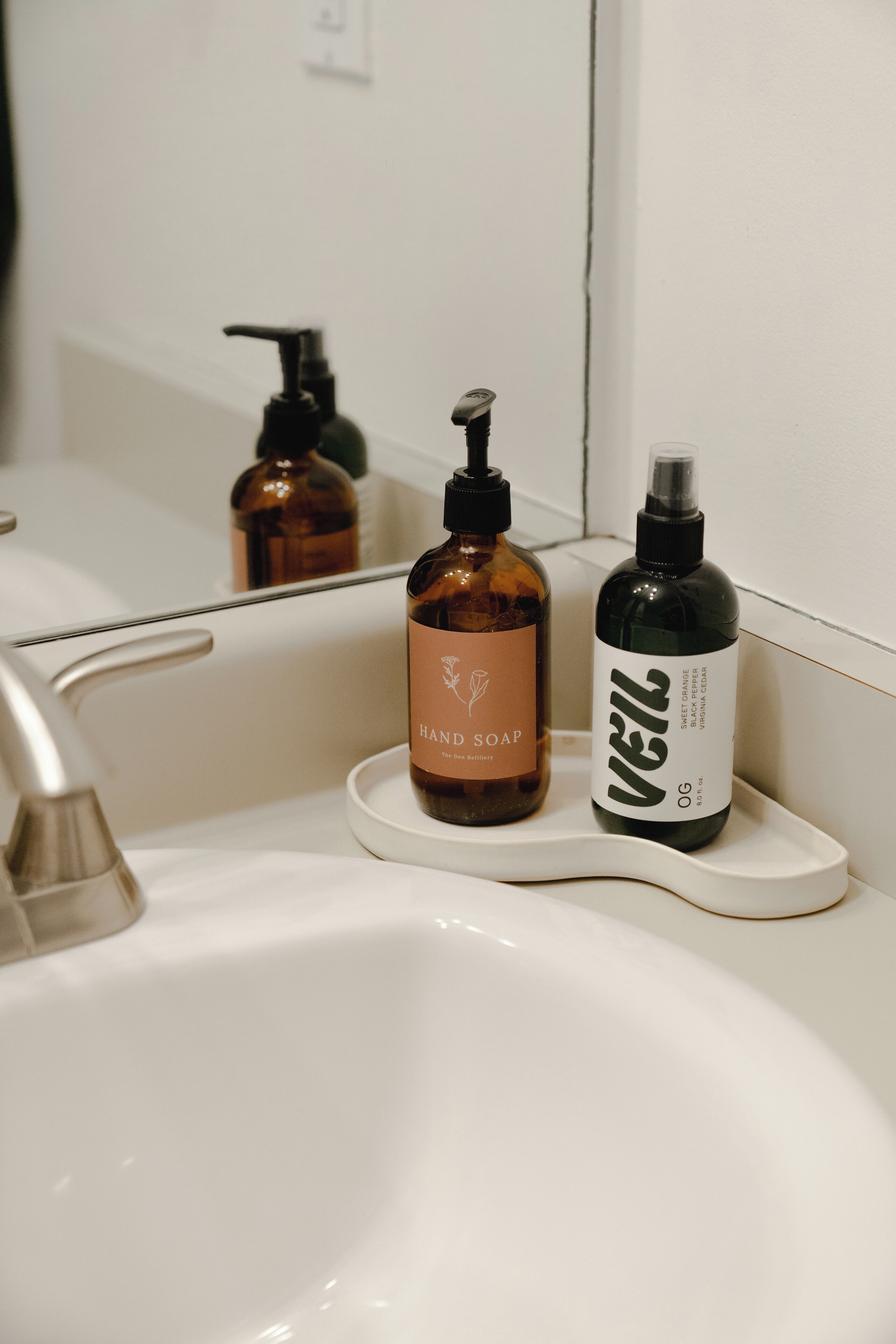 Een wastafel met twee zeepflesjes en een spiegel.