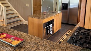 Eine Küche mit Granit Arbeitsplatten, einem eingebauten Backofen, einem Edelstahlkühlschrank und einer Holzeile.