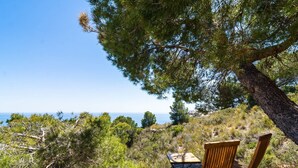 Une terrasse en bois avec une table et deux chaises, offrant une vue sur un paysage côtier.