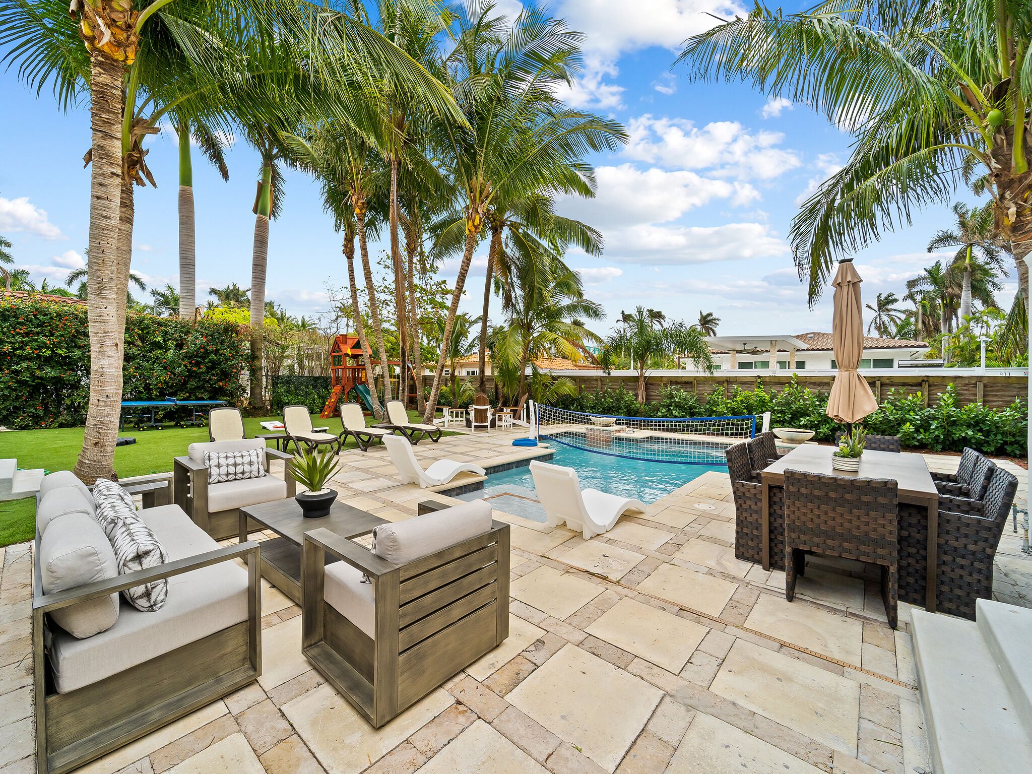 A poolside area with lounge chairs, a small table, and a children's play structure.