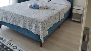 A bedroom with a bed, a nightstand, a wall-mounted air conditioner, and decorative wall art. - Otuz5 Otel (Cesme)