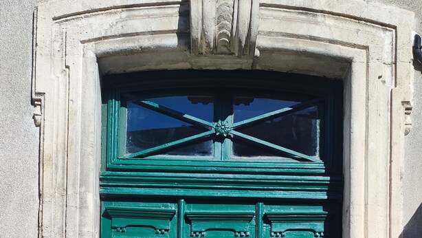 A green double door with a brass handle, flanked by two potted plants, and a stone plaque above. - Charming house downtown ARCEAUX 140M2. 4 bedrooms. Possible Prkg (Montpellier)