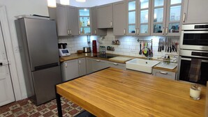A modern kitchen with grey cabinets, a stainless steel refrigerator, a wooden countertop, a built-in oven, and a variety of kitchen utensils. - Charming house downtown ARCEAUX 140M2. 4 bedrooms. Possible Prkg (Montpellier)