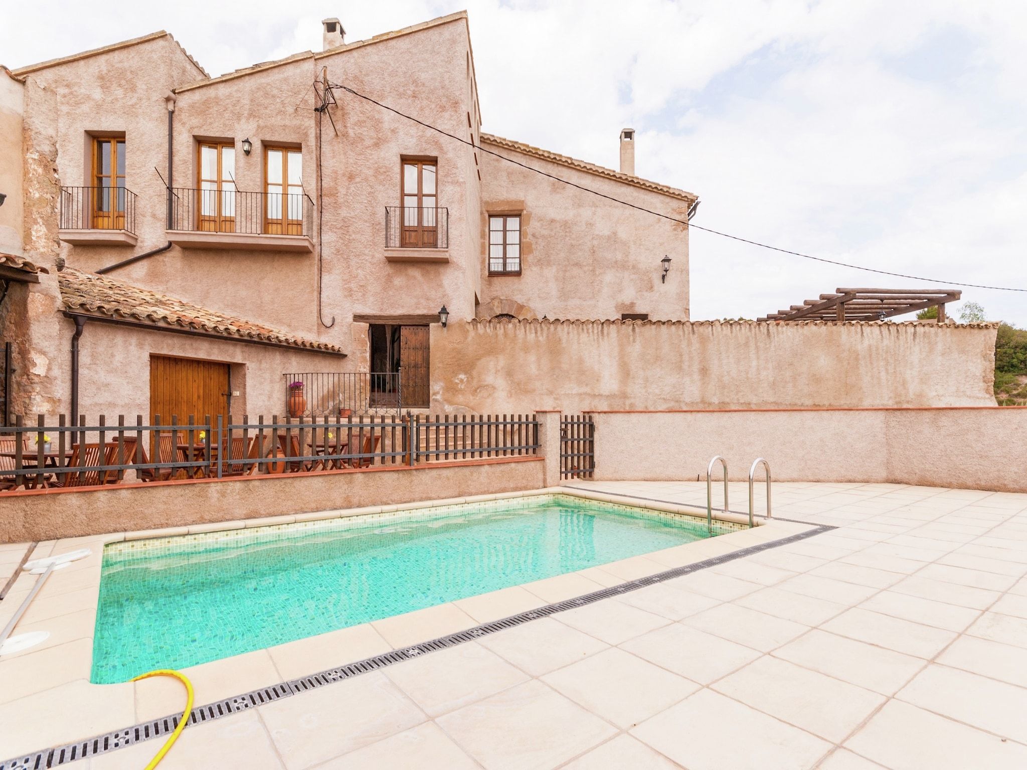 Un bâtiment à deux étages doté d’une piscine, d’un espace extérieur aménagé et d’une terrasse carrelée.