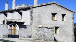 Ein zweistöckiges Steinhaus mit Ziegeldach, einer kleinen Veranda und einem befestigten Eingang.