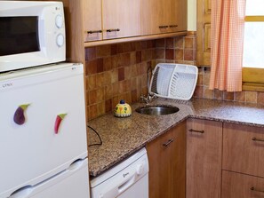 A kitchen with wooden cabinets, a white refrigerator, a microwave, a sink, and a dish rack. - Cottage in Maians with Pool and Garden (Maians - Castellfollit del Boix)