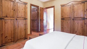 Un dormitorio con cama, armario de madera y puerta que da a otra habitación.