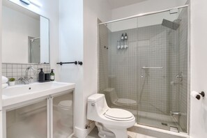 A modern bathroom with a glass-enclosed shower, a white sink, and a toilet. - Take a break in a modern loft on the plateau (Montréal)
