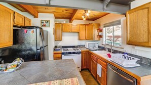 Una cocina compacta con armarios de madera, un refrigerador, estufa, microondas y lavavajillas.
