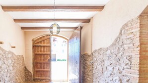 Un pasillo estrecho con una puerta de madera y una pared de piedra a un lado.