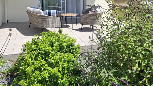Une maison moderne dotée d’une grande porte vitrée donnant sur un patio abrité.