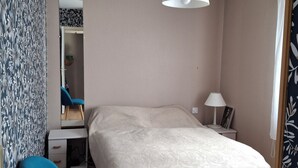 Une chambre à coucher comprenant un lit, un bureau, une chaise, une armoire et un luminaire suspendu.