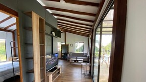 Uma sala de estar moderna com piso de madeira, estantes embutidas, uma TV de tela plana, um sofá e uma porta de vidro que dá para uma área externa.