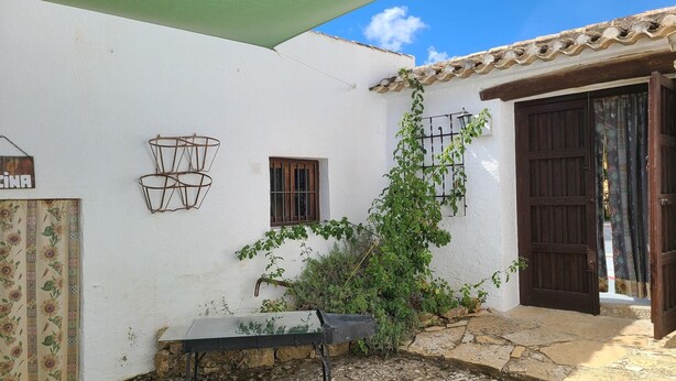 Un edificio blanco con techo de tejas, una ventana pequeña y una puerta con cortina.