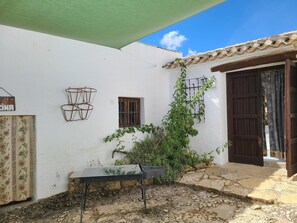 A white building with a tiled roof, a small window, and a door with a curtain. - Peaceful Farmhouse Retreat (Fuentes de Cesna)