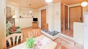 En hyggelig stue med træloft, et spisebord med stole, en sofa og et fjernsyn.