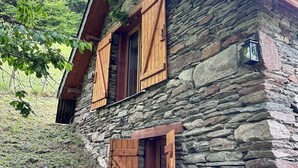 Ein rustikales Steinhaus mit Holzhörnern, einem Schornstein und einem kleinen Fenster mit Laterne.
