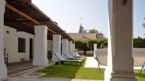A covered outdoor area with white pillars, a tiled roof, and a row of sun loungers. - Costa del Sol Villa Near Beach (San Pedro de Alcantara)