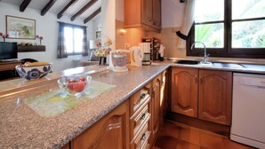 Una cucina con mobili in legno, piani in granito, una macchina per il caffè e una lavastoviglie.