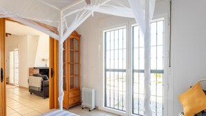 A bedroom with a bed, a wooden wardrobe, a radiator, and a window with a view of the outside. - Villa in Arenas with Sea Views and Private Pool (Arenas)