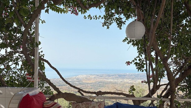 A bed with a view of a cityscape, a hanging lantern, and a tree branch overhead. - Villa in Arenas with Sea Views and Private Pool (Arenas)